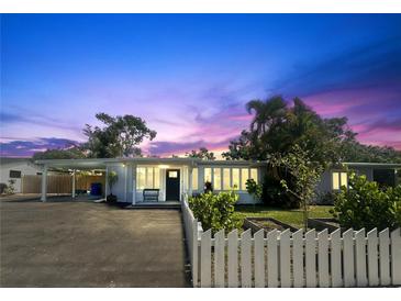 Charming single-story home with a well-manicured lawn and white picket fence at sunset at 1200 47Th St N, St Petersburg, FL 33713