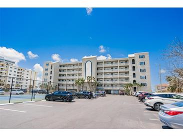 Exterior view of building featuring many floors of condos with a full parking lot and tennis court at 17500 Gulf Blvd # 407, Redington Shores, FL 33708