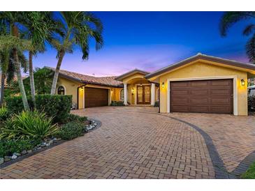 Stunning exterior of a yellow stucco home with a tile roof and a circular driveway lined with palm trees and manicured landscaping at 1931 Kentucky Ne Ave, St Petersburg, FL 33703
