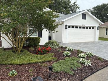 Charming home featuring a landscaped front yard with vibrant plantings and a brick driveway at 20938 Sunsweet Ct, Land O Lakes, FL 34637
