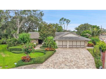 Charming exterior of a home featuring lush landscaping and a paver driveway at 3207 Hilltop Ln, Largo, FL 33770