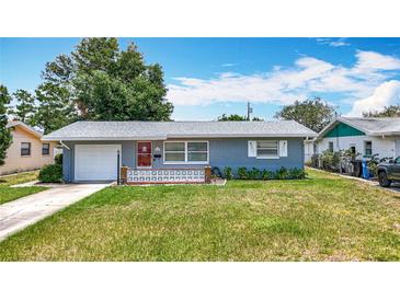 Charming single-story home featuring a well-manicured lawn, red front door, and attached garage at 3271 36Th N St, St Petersburg, FL 33713
