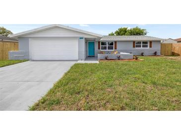 Charming single-story home with a well-maintained lawn and a striking turquoise front door at 6804 Tierra Verde St, Port Richey, FL 34668
