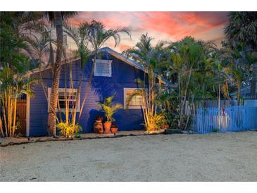 Charming blue home with tropical landscaping and a white picket fence at 722 Gulf Blvd, Indian Rocks Beach, FL 33785