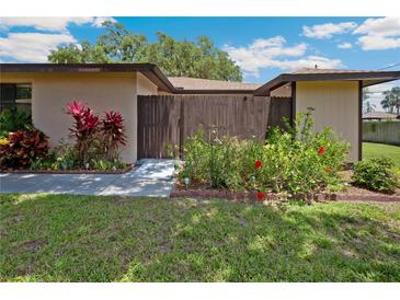 Inviting home exterior with lush lawn, colorful landscaping, and a charming gated courtyard entrance at 8436 60Th N St # 304, Pinellas Park, FL 33781