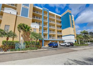 Low-angle view of a multi-story tan and blue condo building with parking at 960 Starkey Rd # 2405, Largo, FL 33771