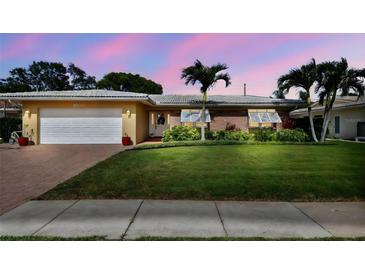 Charming single-story home featuring a well-manicured lawn, brick accents, and a two-car garage at 10387 Majestic Dr, Largo, FL 33774