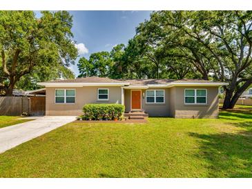 Charming single-story home featuring a well-manicured lawn, mature trees, and inviting curb appeal at 1403 W Pradera Ave, Tampa, FL 33612