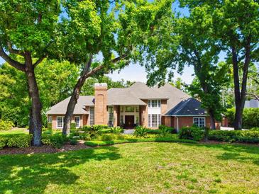 Stately brick home with mature trees, lush landscaping, and a well-manicured lawn at 16502 Millan De Avila, Tampa, FL 33613