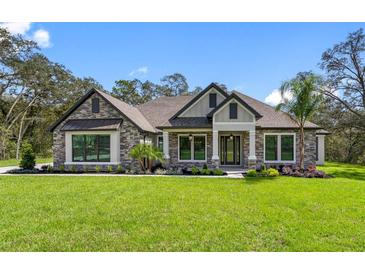 Beautiful stone-accented home with lush lawn and meticulous landscaping under a blue sky at 17404 Nokota Ave, Hudson, FL 34667