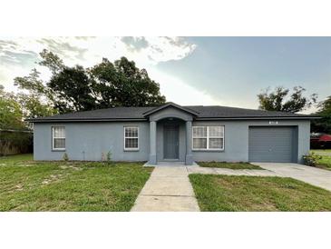 Charming single-story home with gray exterior, well-maintained lawn, and an attached garage at 404 Water St, Plant City, FL 33563