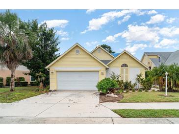 Charming yellow home featuring a two-car garage, well-maintained landscaping and a welcoming front entrance at 7833 Ontario Street Cir, Sarasota, FL 34243