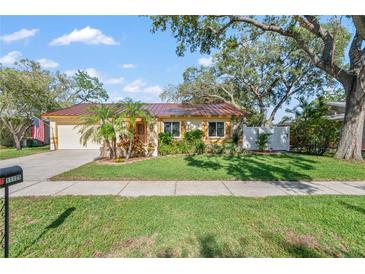 Charming single-story home featuring a lush green lawn, mature trees, and a light yellow exterior at 11125 117Th St, Seminole, FL 33778