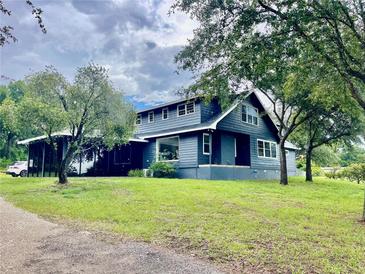Charming two-story home features a well-manicured lawn, mature trees, and a side entry covered parking at 13400 10Th St, Dade City, FL 33525