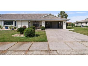Well-maintained single-story home with a carport and manicured front lawn and mature landscaping at 1633 Bentwood Dr, Sun City Center, FL 33573