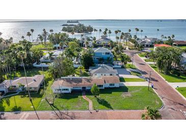 Stunning aerial view of coastal homes with manicured lawns and views of the bay in the distance at 1794 Santa Barbara Dr, Dunedin, FL 34698