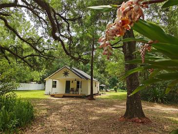 Charming home featuring a covered porch and lovely landscaped front yard in a verdant setting at 18452 Fort Dade Ave, Brooksville, FL 34601