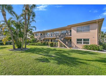 Two-story condo building with lush green lawn, mature palms, and private entrances via exterior staircases at 216 36Th N Ave # 202B, St Petersburg, FL 33704