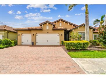 Charming home featuring a brick driveway, manicured landscaping, and a spacious three-car garage at 222 Toscavilla Blvd, Nokomis, FL 34275