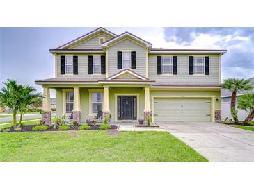 Two-story home with a two-car garage, front porch with stone accents, and manicured lawn at 3012 Magnolia Meadows Dr, Plant City, FL 33567