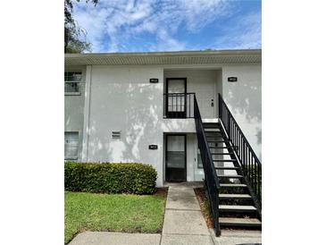Condominium exterior showing the front entrances with a staircase and well-maintained landscaping at 3802 N Oak Dr # W22, Tampa, FL 33611