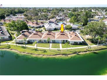 An aerial view of a waterfront townhome featuring a lush green lawn and scenic water views at 4324 Tahitian Gardens Cir # J, Holiday, FL 34691