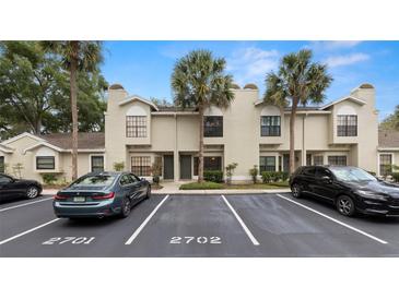 Townhouse exterior featuring neutral paint, a well manicured landscape, and ample parking with mature palm trees at 5100 Burchette Rd # 2702, Tampa, FL 33647
