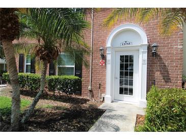Inviting brick home with a front door framed by lush tropical landscaping and a charming arched entryway at 13755 Orange Sunset Dr # 101, Tampa, FL 33618