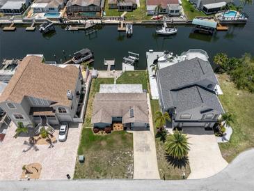Stunning aerial view of a waterfront home with boat docks, lush landscaping, and a well-maintained yard at 15713 Century Dr, Hudson, FL 34667