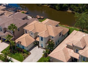 An aerial view of a two-story home boasting a tile roof, paved driveway and access to the water at 18050 Cozumel Isle Dr, Tampa, FL 33647