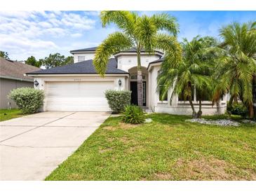 Charming two-story home with lush landscaping, palm trees, and a well-maintained lawn creating a welcoming curb appeal at 27353 Edenfield Dr, Wesley Chapel, FL 33544