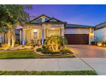Charming home featuring manicured landscaping and a brick driveway leading to an attached two-car garage at 31921 Magna Gulf Loop, San Antonio, FL 33576