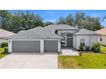 Beautiful single-story home featuring a three-car garage, well-maintained lawn, and neutral color palette at 403 Carriage House Ln, Tarpon Springs, FL 34688