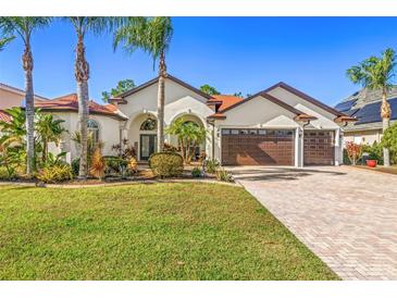 Stunning single-story home with a three-car garage, lush landscaping, and a brick-paved driveway at 10724 Cory Lake Dr, Tampa, FL 33647