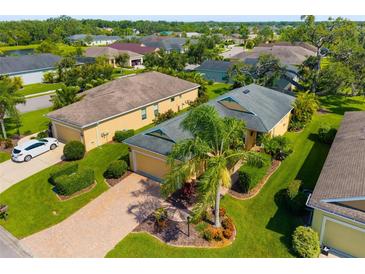 Aerial view of a well-maintained home with lush landscaping, a brick driveway, and a serene neighborhood setting at 11813 Crawford Parrish Ln, Parrish, FL 34219