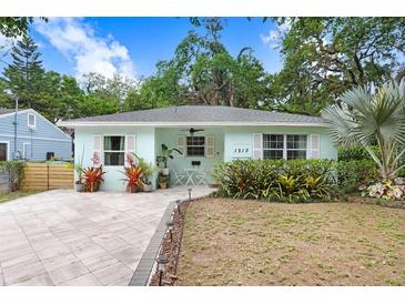 Charming light-blue home with well-manicured lawn, stone pathway, and inviting front porch area at 1213 E Idlewild Ave, Tampa, FL 33604