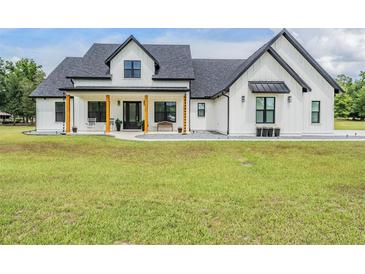 Stunning modern farmhouse with white siding, black trim, and inviting front porch at 17566 Hyland Ln, Dade City, FL 33523