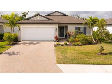 Charming single-story home with well-manicured lawn, mature landscaping, and brick-paved driveway at 5511 Badini Way, Palmetto, FL 34221