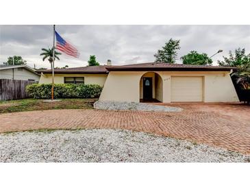 Charming single-story home featuring a brick driveway, landscaped yard, and American flag at 6409 41St N Ave, St Petersburg, FL 33709