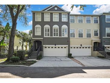 A charming three-story townhome featuring a two-car garage, a cozy entryway staircase, and a well-maintained front yard at 1402 Harbour Walk Rd, Tampa, FL 33602