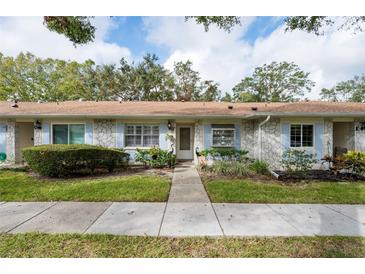 Charming one-story townhome with a well-maintained front lawn and stone facade and concrete pathway at 2238 Lark W Cir # D, Palm Harbor, FL 34684