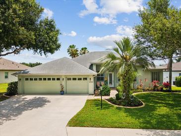 Charming single-story home with a well-manicured lawn, palm trees, and a three-car garage at 2730 River Woods Dr, Parrish, FL 34219