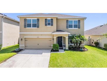 Inviting two-story home featuring a well-maintained lawn, and a two-car garage at 30989 Summer Sun Loop, Wesley Chapel, FL 33545