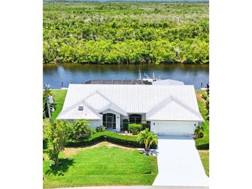 Stunning waterfront home with lush landscaping, bright white exterior, and private dock at 3936 Crooked Island Dr, Punta Gorda, FL 33950