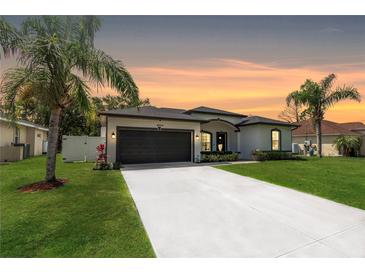 Charming single-story home with a well-manicured lawn, palm trees, and a freshly painted driveway at 4264 Michaler St, North Port, FL 34286