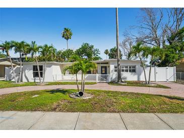 Charming single-story home boasting a beautifully landscaped yard with mature palm trees and a circular driveway at 709 Pruitt Dr, Madeira Beach, FL 33708