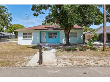 Charming single-story home featuring a light blue exterior, a cozy front yard, and a concrete walkway leading to the front door at 8525 N Ola Ave, Tampa, FL 33604