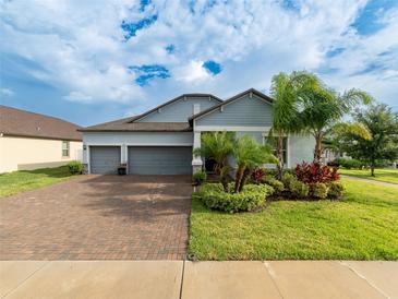 Charming single-Gathering home with a three-car garage, brick driveway, and tropical landscaping at 11714 Sunburst Marble Rd, Riverview, FL 33579