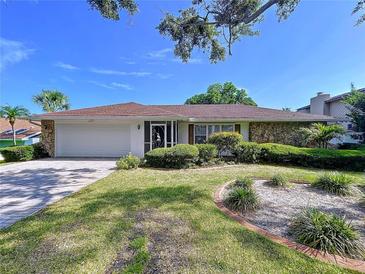Charming single-story home with a well-manicured front yard, stone accents, and beautiful landscaping at 13725 Oak Forest N Blvd, Seminole, FL 33776