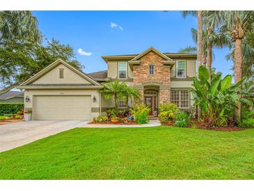 Inviting two-story home with stone facade, lush landscaping, and a well-manicured lawn at 3000 Naughton Way, Tarpon Springs, FL 34688